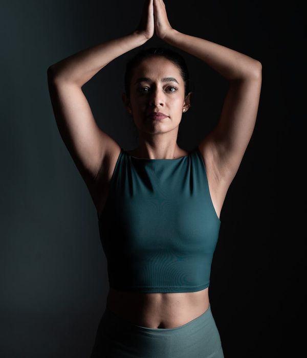 Woman in a calm yoga pose against a dark background with lime green light.